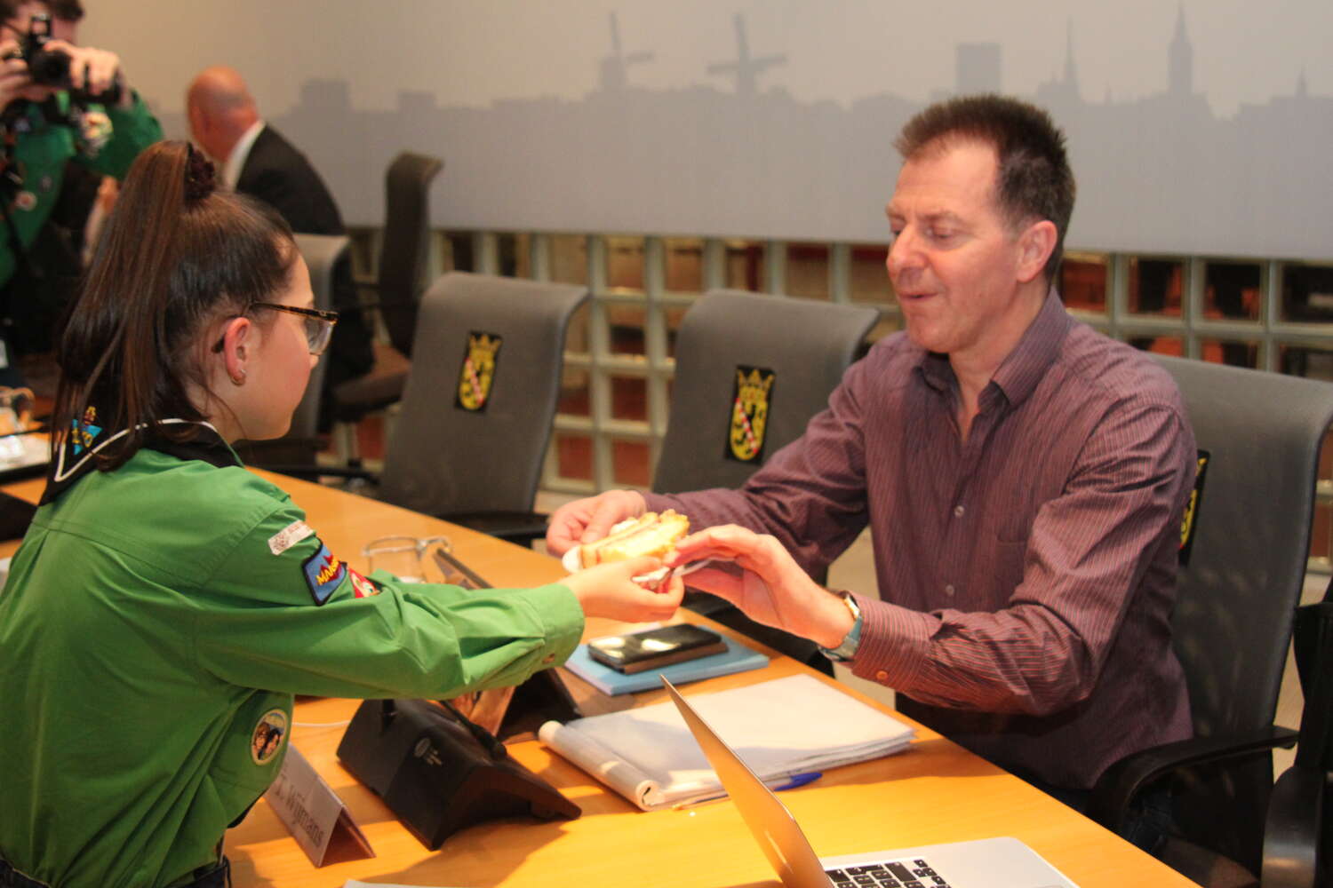 De welpen delen taart uit aan de gemeenteraadsleden van Schiedam om samen 100 jaar welpen in Nederland te vieren